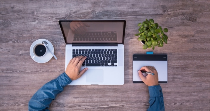 Das Bild zeigt einen Mann der an einem Laptop sowie einem Tablett arbeitet. Das Bild dient als Titelbild zu unserem Stellenangebot im Bereich Webdesign